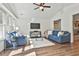 Inviting living room with hardwood floors, blue sofas, a ceiling fan, and large windows providing ample natural light at 108 Shawville Ln, Peachtree City, GA 30269