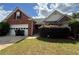 Traditional brick home featuring an attached two-car garage and a well-maintained lawn under a partly cloudy sky at 124 Sparkling Spring Trl, Mcdonough, GA 30252
