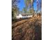 Exterior view of the white painted house, fenced yard, and lush backyard with mature trees and covered in pine straw at 1905 Robinhill Ct, Tucker, GA 30084