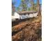 Exterior view of the white painted house, fenced yard, and lush backyard with mature trees and covered in pine straw at 1905 Robinhill Ct, Tucker, GA 30084