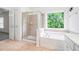 Bright primary bathroom with large garden tub, shower and tiled floor at 2717 High Creek Run, Dacula, GA 30019