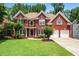 Charming two-story brick home with a manicured lawn, mature trees, and an attached two-car garage at 3944 Blustery Ne Way, Marietta, GA 30066