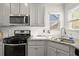 Close-up of a kitchen features granite countertops, stainless steel appliances, white backsplash, and gray cabinets at 1511 Arica Ave, Lawrenceville, GA 30043