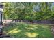 Lush backyard with green grass, mature trees, garden beds, and a privacy fence at 4865 Fenbrook Dr, Stone Mountain, GA 30088