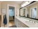 Bright bathroom featuring double sinks with white cabinetry, a large mirror, and black and white tile flooring at 285 Lackland Court, Sandy Springs, GA 30350
