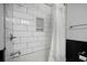 Close up of subway-tile shower with shelf niche, black trim, and shower curtain at 184 Rambo Sw Pl, Marietta, GA 30064