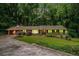 Charming home boasts a lush, green lawn and a circular driveway surrounded by mature trees at 5170 Oxbow Rd, Stone Mountain, GA 30087