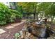 Beautiful backyard water feature with stone pathway, mature landscaping, and bench swing at 230 Leaf Court, Alpharetta, GA 30005