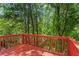 A wooden deck with a bright red railing surrounded by lush green trees at 4910 Longcourt Se Trce # 13, Atlanta, GA 30339
