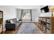 Cozy living room with a gray couch, large window, and decorative shelving, creating a relaxing atmosphere at 516 Broad Head Pt, Suwanee, GA 30024