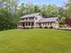 Charming two-story home with a covered front porch and a lush green lawn surrounded by mature trees at 7720 Milam Rd, Winston, GA 30187