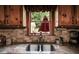 A bright kitchen features a granite countertop, stainless steel sink, and a window overlooking the backyard, offering charm and functionality at 7720 Milam Rd, Winston, GA 30187