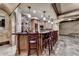Stylish basement bar featuring stone arches, wood cabinetry, pendant lighting, and seating for entertaining guests at 8525 Saint Marlo Fairway Way, Duluth, GA 30097