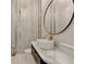 Elegant bathroom featuring marble walls, a chandelier, a round mirror, and a sleek oval sink at 8525 Saint Marlo Fairway Way, Duluth, GA 30097