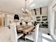 Open-concept dining area with modern light fixtures, wooden table with seating, and a view of the kitchen at 8525 Saint Marlo Fairway Way, Duluth, GA 30097