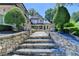 Stately stone steps lead to an elegant brick home with manicured landscaping and a water fountain feature at 8525 Saint Marlo Fairway Way, Duluth, GA 30097