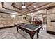 Spacious basement game room with a pool table and bar area with recessed lights and stone walls at 8525 Saint Marlo Fairway Way, Duluth, GA 30097