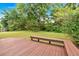 Backyard with a wood deck and bench seating surrounded by green grass and trees at 3035 Landington Way, Duluth, GA 30096