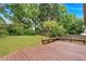 Backyard with a wood deck and bench seating surrounded by green grass and trees at 3035 Landington Way, Duluth, GA 30096
