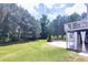 A landscaped backyard featuring green grass, mature trees, and a patio at 149 Stargrass Way, Grayson, GA 30017