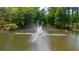Scenic pond featuring a central water fountain, surrounded by lush greenery at 25305 Plantation Ne Dr, Atlanta, GA 30324