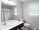 Well-lit bathroom featuring a vanity, toilet, mirror, and shower with a patterned curtain at 3075 Milford Sw, Marietta, GA 30008