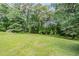 Spacious backyard with a large green lawn, surrounded by mature trees at 3920 Stonewall Tell Rd, Atlanta, GA 30349