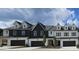 Modern townhomes featuring painted brick, dark trim, dormer windows, and individual garages, all under a cloudy sky at 210 Sharon Ln, Loganville, GA 30052