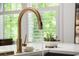 Close up of a bronze kitchen faucet with flowing water and light countertop at 262 Southerland Ne Ter, Atlanta, GA 30307