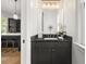 Stylish powder room with dark vanity, elegant mirror, and view into the adjacent kitchen at 262 Southerland Ne Ter, Atlanta, GA 30307