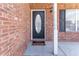 Close-up of front door with oval glass insert, decorative light fixture and red brick surround at 538 Shadowmoore Dr, Riverdale, GA 30274