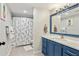 Bathroom features a blue vanity, a white countertop, a large mirror, and a shower with patterned curtain at 2356 Defoors Ferry Nw Rd, Atlanta, GA 30318
