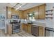 Charming kitchen featuring wood cabinets, stainless steel appliances, and a modern lighting fixture at 2920 Waverly Place Dr, Dacula, GA 30019