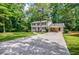 Well-maintained two-story house with a spacious driveway and carport amid mature trees at 4493 Orleans Dr, Dunwoody, GA 30338