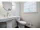 Bright powder room features a pedestal sink with a decorative mirror and a window with natural light at 4493 Orleans Dr, Dunwoody, GA 30338