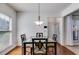 Dining area featuring a glass table, contemporary chandelier, hardwood floors, and large window for natural light at 4619 Sweetwater Ave, Powder Springs, GA 30127