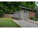 View of the home's side exterior with a gravel driveway, gray siding, and partial brick feature at 1140 Allgood Rd, Stone Mountain, GA 30083