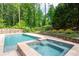 Backyard pool and hot tub feature stone accents, lush landscaping, mature trees, and a fenced perimeter at 355 Clark Creek Pass, Acworth, GA 30102