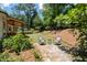 Landscaped backyard with a stone pathway leading to a seating area and mature trees at 4390 Wicklow Ct, Suwanee, GA 30024