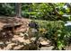 Landscaped backyard with a charming waterfall feature surrounded by lush greenery and a quaint stone bench at 4390 Wicklow Ct, Suwanee, GA 30024