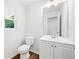 Compact half bathroom featuring a white vanity, toilet, and a window for natural light at 132 2Nd Nw St, Atlanta, GA 30318