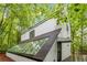 Rear view of modern home featuring greenhouse and partial deck with surrounding trees at 165 River North Walk, Atlanta, GA 30328