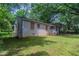 Side view of a single story home with a fenced backyard, boarded windows and a large lawn at 1906 Oak Valley Rd, Decatur, GA 30035