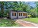 Charming exterior view of a compact home with a brick foundation, boarded-up windows, and mature trees at 1906 Oak Valley Rd, Decatur, GA 30035