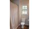 Bathroom with a neutral shower curtain, toilet, and window providing natural light at 237 Arborview Dr, Mcdonough, GA 30252