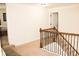 Hallway with stairs and banister, leading to an open space with neutral carpet at 237 Arborview Dr, Mcdonough, GA 30252