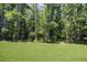 Lush backyard featuring mature trees, an expansive lawn, and a charming wooden fence at 1150 Sweet Mia Ln, Powder Springs, GA 30127