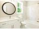 Bright bathroom with a large mirror, white cabinets, quartz countertops, and tiled bathtub at 1150 Sweet Mia Ln, Powder Springs, GA 30127