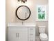 Bathroom with vanity, lighting, round mirror, and white toilet at 1150 Sweet Mia Ln, Powder Springs, GA 30127