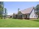 A house sits on a large lot with mature trees, featuring neutral siding, a brick foundation, and a covered patio at 1150 Sweet Mia Ln, Powder Springs, GA 30127